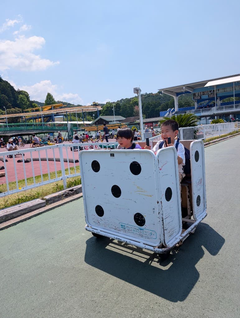 TGA students laughing while riding a dice-themed cart at the Kansai Cycle Sports Center