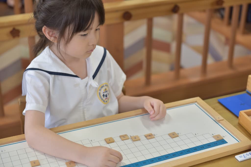 Student concentrating on a Montessori math board