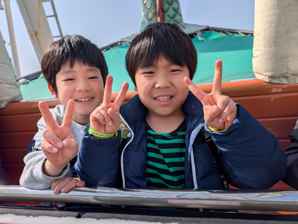 Tezukayama Global Academy students in school uniforms sitting together on a Japanese commuter train during a school field trip