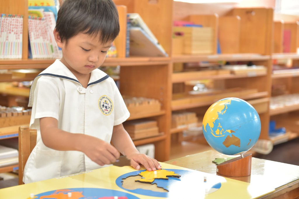 Student placing continents on a Montessori world map puzzle