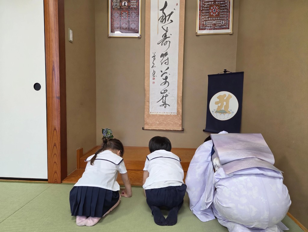 TGA students and a kimono-clad instructor bowing together during a traditional tea ceremony lesson